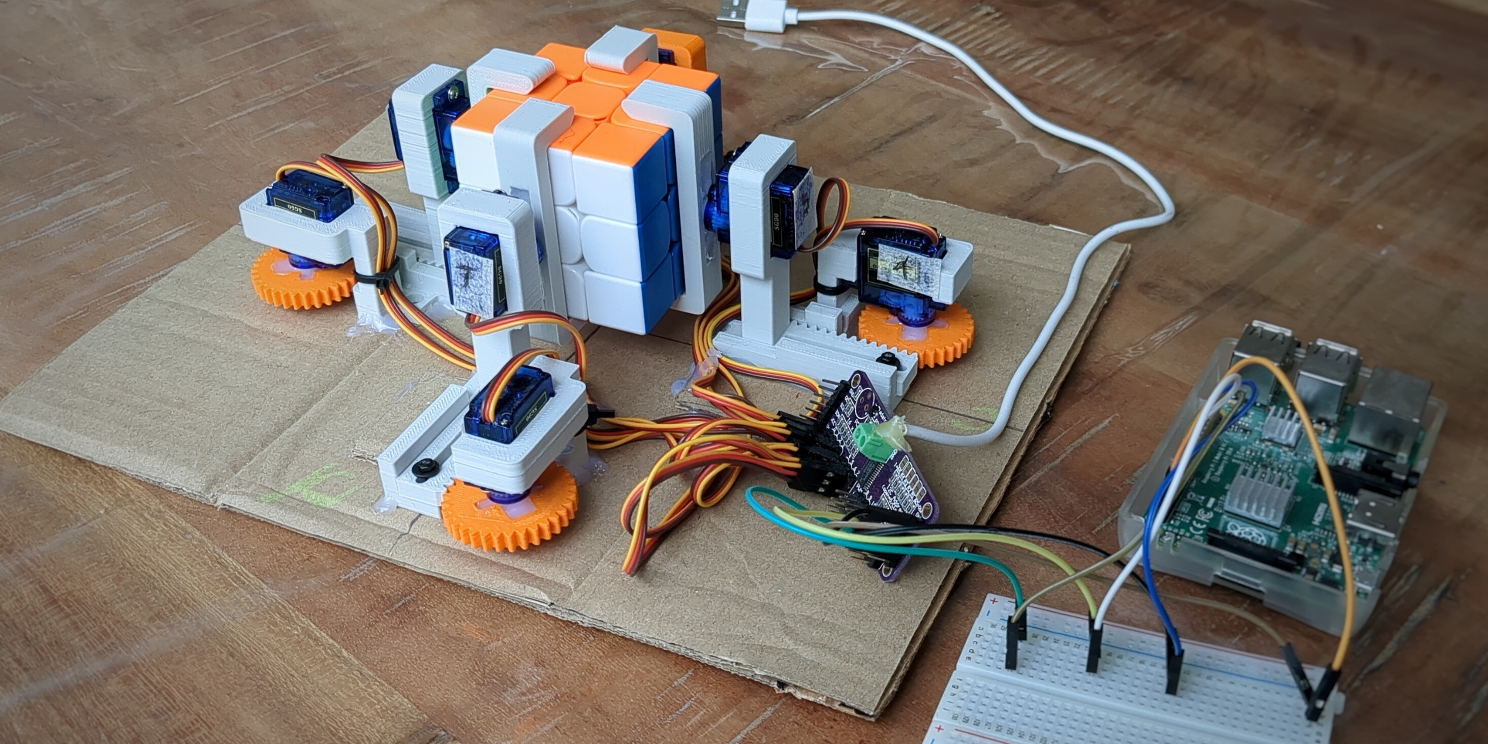 Picture of a Rubik's cube solver using 8 servos. The servos are configured to move a gripper in and out and rotate a face of the cube. The system is controlled by a Raspberry Pi 2B.